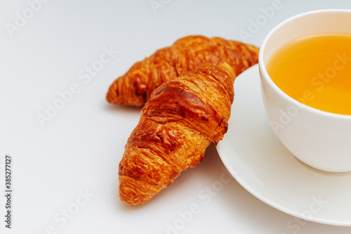 Croissants with a cup of tea on a white background. Breakfast with a cup of black coffee, croissant on white plate isolated on white background.