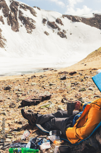 Traveler drinks tea while enjoying the view of mountains.