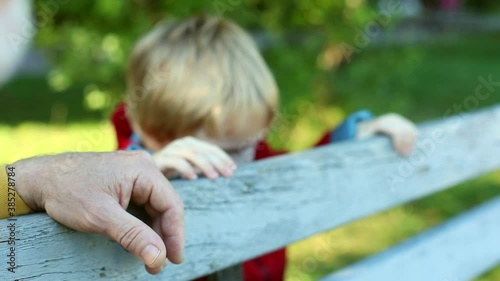 Little blonde boy playing outside with grandpa on blurred background. Sunny beautiful day. Family ties. Conscious parenting concept. Healthy family lifestyle. Kids fashion. Playful toddler. Portrait.