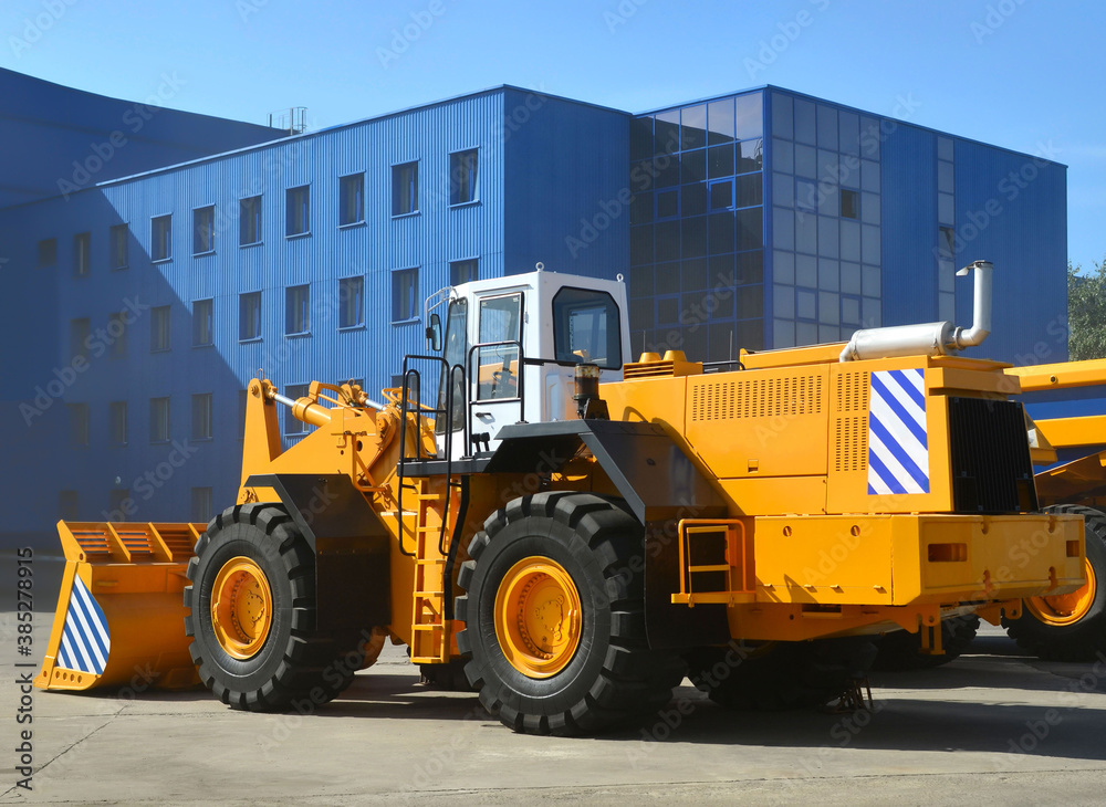Obraz premium Wheel loader machine for handling bulk materials in an open pit or construction site. Heavy quarry equipment with bucket. Heavy quarry equipment with bucket. Mining vehicle