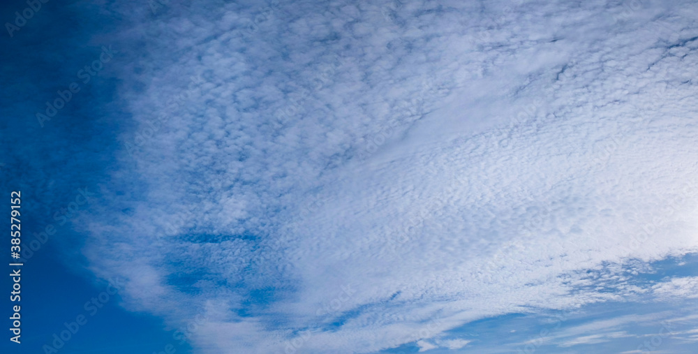 Bright blue cloudy sky background. Panoramic view, wide banner.