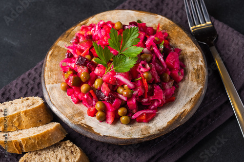 Vegetarian vegetable vinigret in a round clay plate on a dark background with copy space