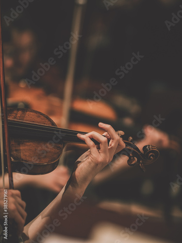 Close frame for the hand of a violinist of a symphony orchestra.