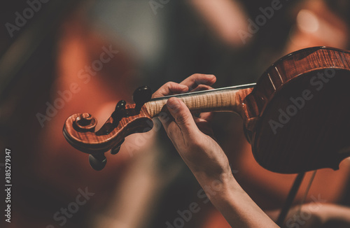 Close frame for the hand of a violinist of a symphony orchestra.