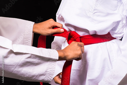Taekwondo woman tying her red belt and getting ready for training.