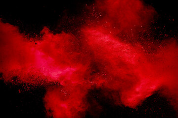 Red powder explosion on black background. Freeze motion of red dust particles splash.