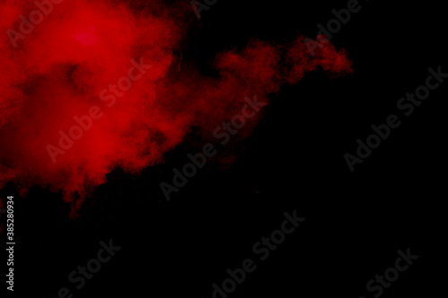 Red powder explosion on black background. Freeze motion of red dust particles splash.