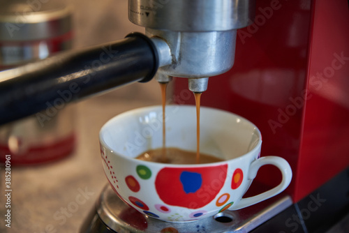 Brewing coffee with a coffee machine. Closeup of a coffee machine. Colorful mug.
