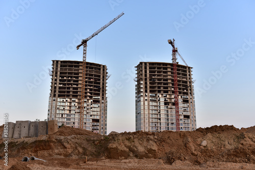 Tower cranes in action at construction site on sunset background. Construction of skeleton of modern residential buildings. Preparing to pour of concrete into formwork. Erection multi-storey building © MaxSafaniuk