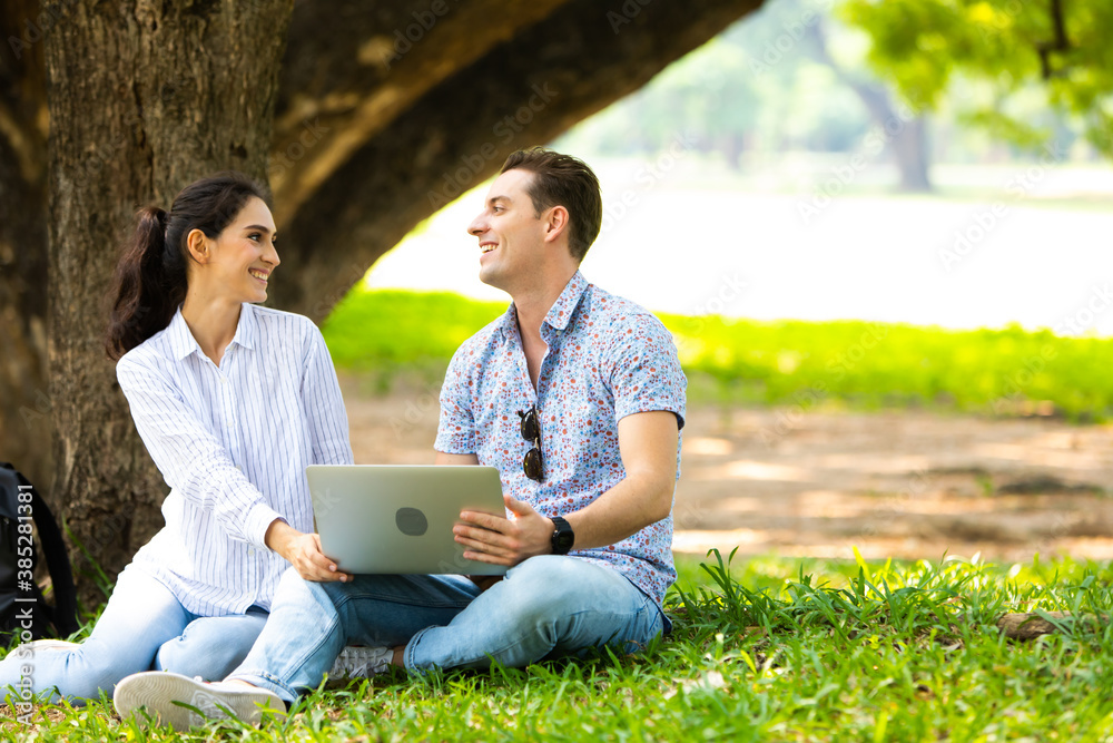 Romantic couple in love concept. Couple sitting on grass and using laptop computer in park on a holiday day. Online shopping Romantic couple in love concept. Couple sitting on grass and using laptop computer in park on a holiday day. Online shopping