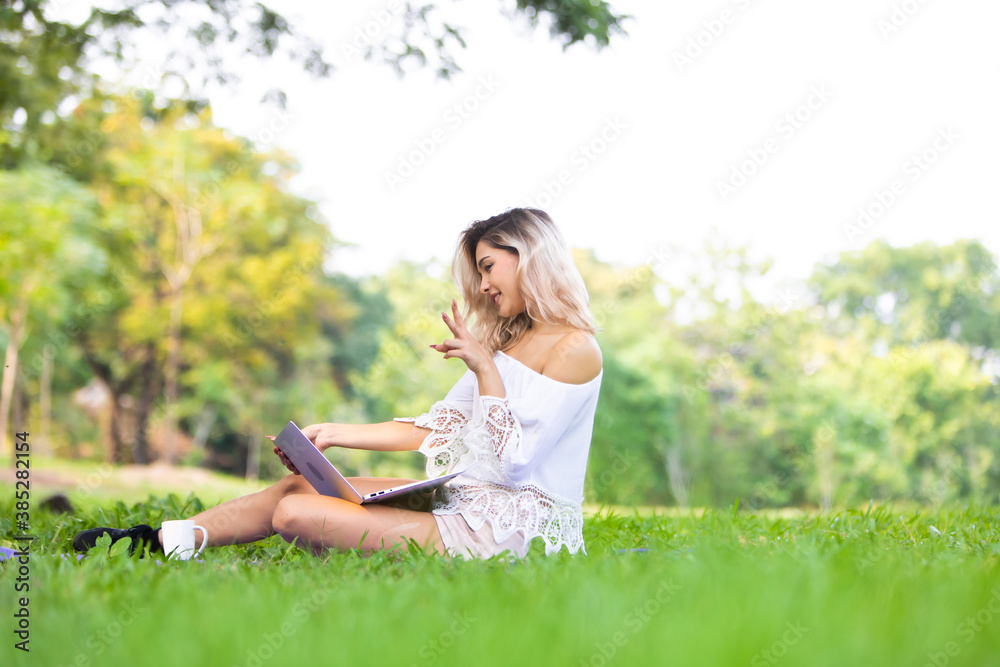 Portrait of pretty young student woman sitting on green grass in park with laptop computer. Portrait of pretty young student woman sitting on green grass in park with laptop computer.