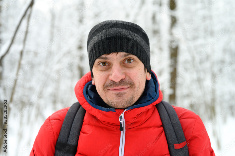 portrait of a happy young man in a red jacket and hat in a snowy winter forest portrait of a happy young man in a red jacket and hat in a snowy winter forest