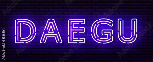 Glowing neon sign with the inscription of the Korean city of Daegu. In blue and purple colors. Against a brick wall.