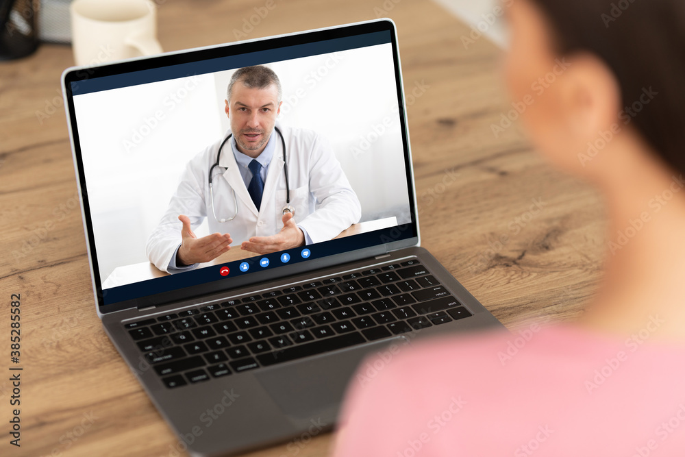 Woman having video chat with doctor on laptop at home - obrazy, fototapety, plakaty 