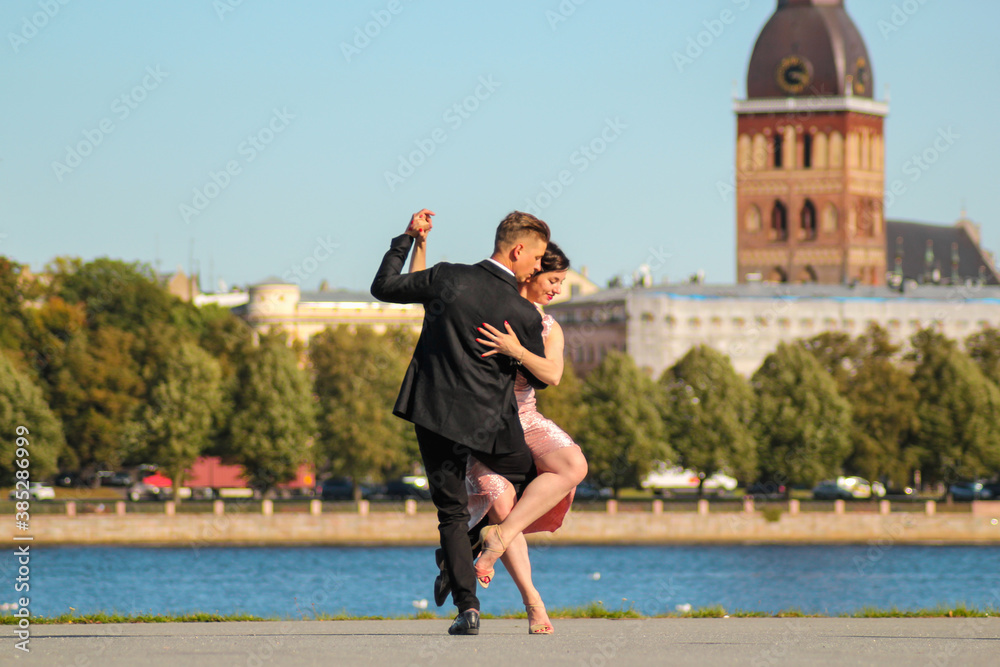 Young couple dancing tango against the old city background. Travel and lifestyle concepts - obrazy, fototapety, plakaty 