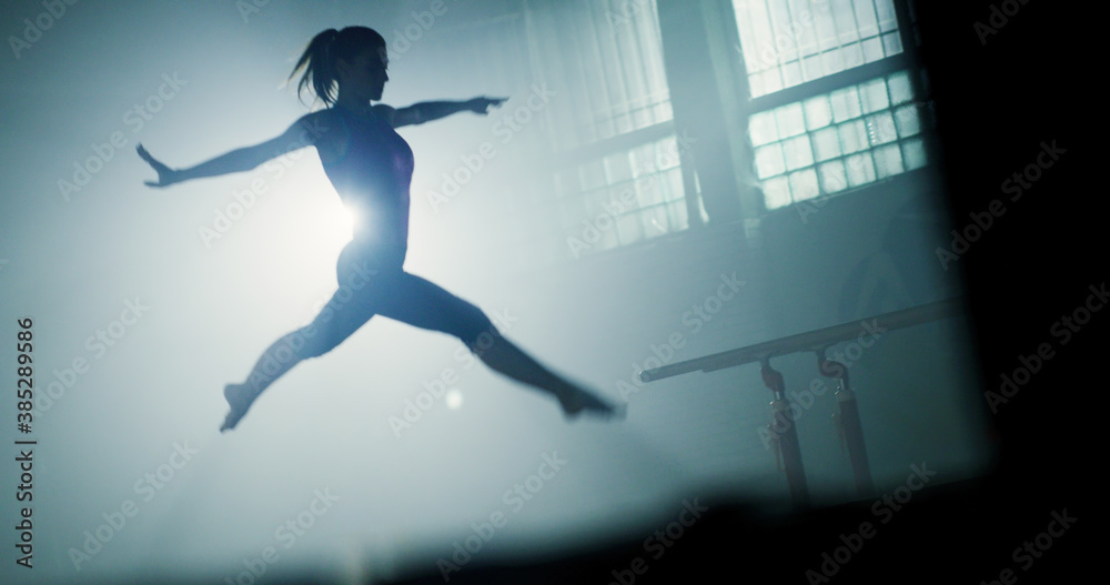 Young Fit Woman Gymnast Doing Cartwheel On Balance Beam In The Gym
