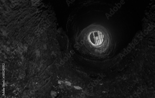 Image of the body of a well portrayed from the bottom. View of the grating at the top, on the mouth.