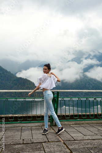 Wallpaper Mural A girl in white clothing on a background of a mountain lake with blue water and mountains with clouds. Background. Torontodigital.ca