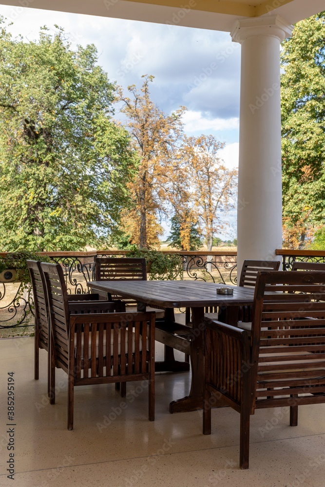 Set of wooden furniture table and chairs on an outdoor terrace overlooking the autumn park