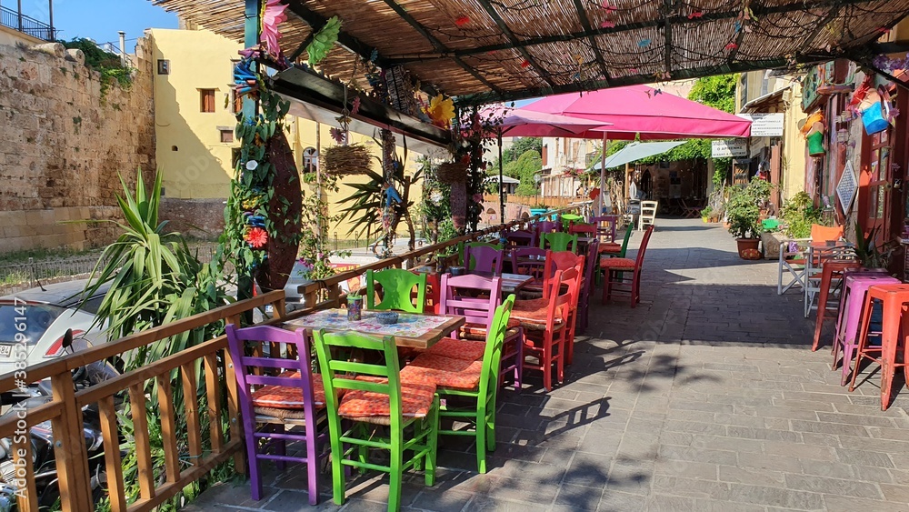 Greek restaurant without people. Colorful chairs and tables outside.