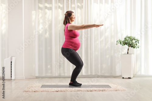 Full length profile shot of a woman doing pregnancy exercises at home