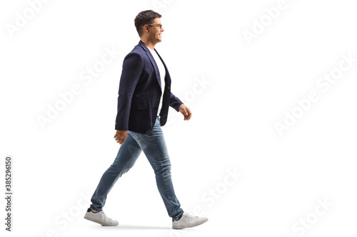 Foto Full length profile shot of a smiling young man in jeans and suit walking