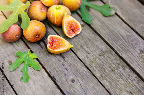 Fresh fig sliced in half with whole figs in the background, on a wooden surface. Fig fruits on a wooden platter.