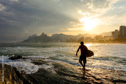 Surfer at sunset in Arpoador beach at Ipanema in Rio de Janeiro