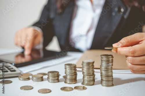 Closeup image businesswoman holding coins putting to stacking coins bank and calculating. concept saving money wealth for finance accounting.
