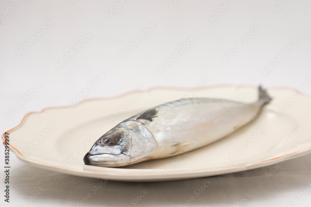 Old decorative presentationdish with tasty raw mackerel fish on table with an embroidered tablecloth Old decorative presentationdish with tasty raw mackerel fish on table with an embroidered tablecloth