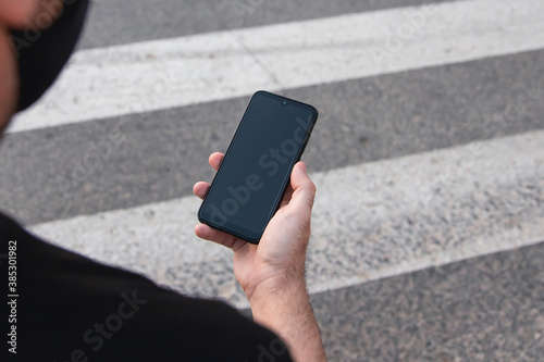 Pedestrian looking at his mobile while crossing the road photo