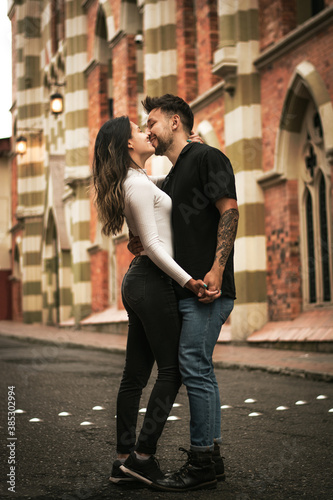 pareja bogotana dandose un beso en una calle del centro de bogotá photo