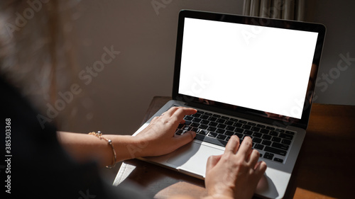 Woman using empty screen laptop at home.