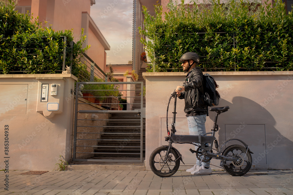 Smiling man with helmet and his electric bicycle at sunset. Commuter ...