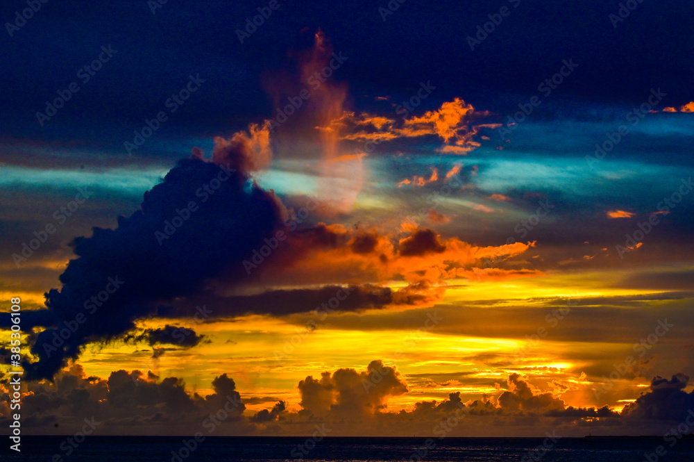 沈む太陽に照らされる橙の雲、群青の空、深青の海