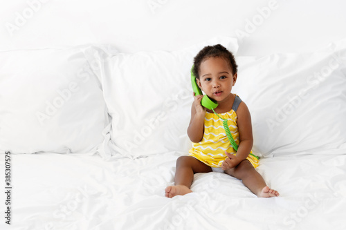 Cute toddler girl holding a green corded phone
