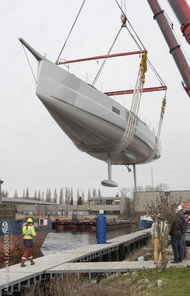 Launch of a super sailing yacht. Lifting and hoisting with cranes. Shipbuilding industry. Launch of a super sailing yacht. Lifting and hoisting with cranes. Shipbuilding industry.