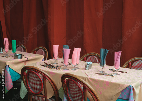 Empty tableset awaiting guests. Colorful cloths and napkins. Silver cutlery. Red stripes curtains. photo