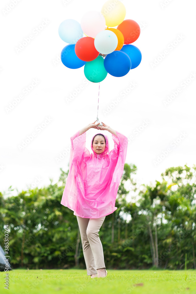 Young beautiful Asian woman wearing a raincoat with color full ballons outdoors