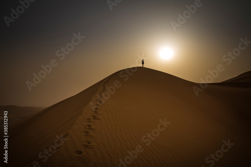 figure walking up a sand dune in Rub al Khali Desert at the Empty Quarter, in Abu Dhabi, UAE