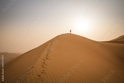figure walking up a sand dune in Rub al Khali Desert at the Empty Quarter, in Abu Dhabi, UAE