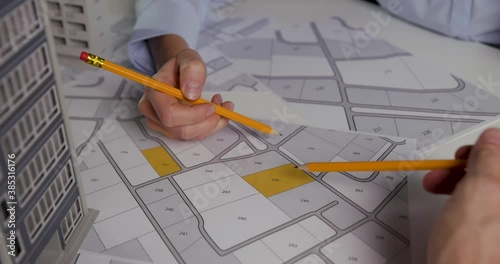 urban planning - businessmen discussing about territory building plots on cadastral map for apartment building construction