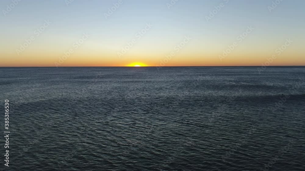 Aerial view of the sun rising in the horizon over a calm moving ocean, at the popular Burleigh Heads Gold Coast QLD Australia Aerial view of the sun rising in the horizon over a calm moving ocean, at the popular Burleigh Heads Gold Coast QLD Australia