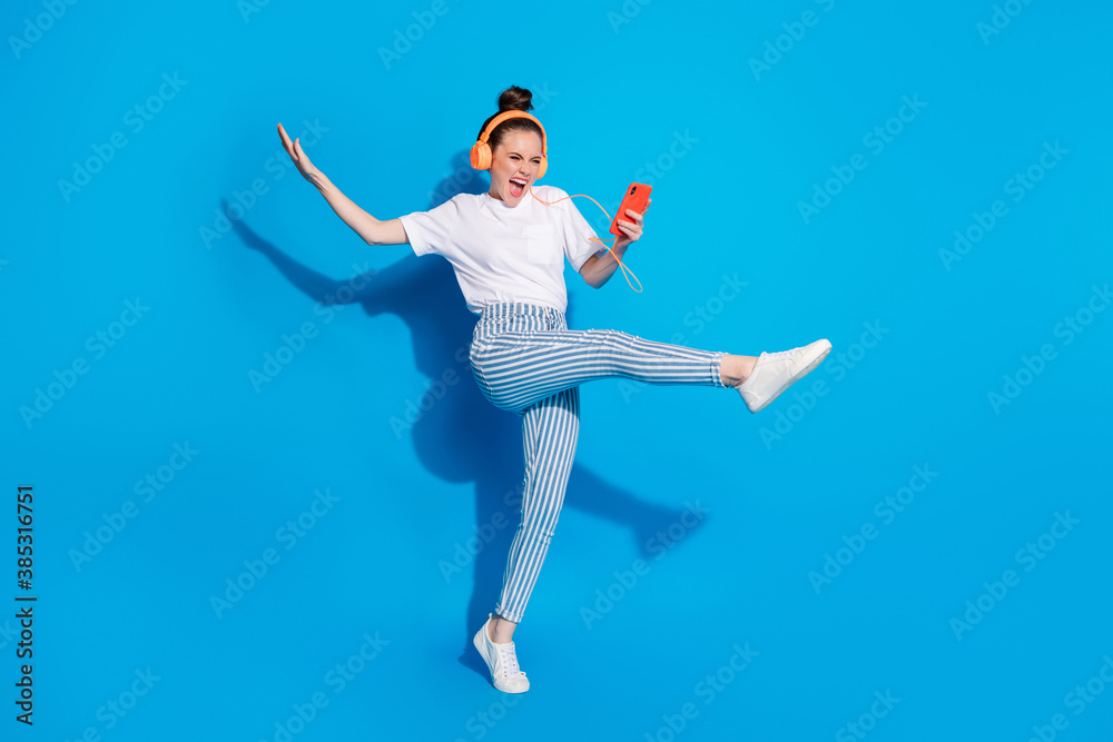 Full length body size view of nice attractive cheerful crazy girl jumping listening pop audio mp3 technology virtual connection isolated on bright vivid shine vibrant blue color background