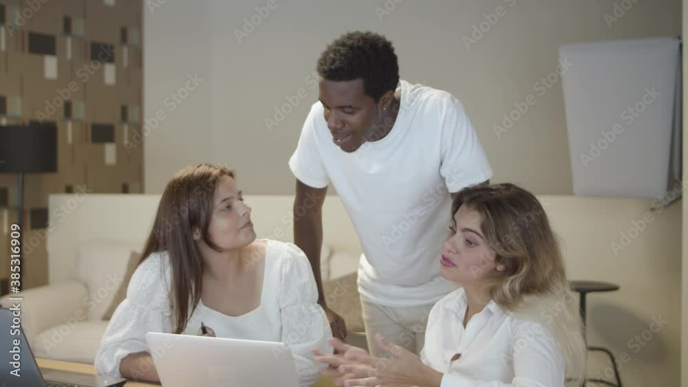 Workgroup sitting and standing at table with laptops, talking, discussing project. Static shot. Collaboration concept Workgroup sitting and standing at table with laptops, talking, discussing project. Static shot. Collaboration concept