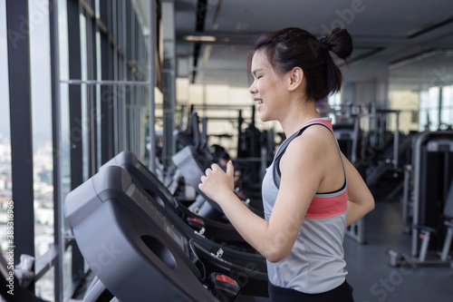 Side View of Asian Woman Jogging on Treadmill