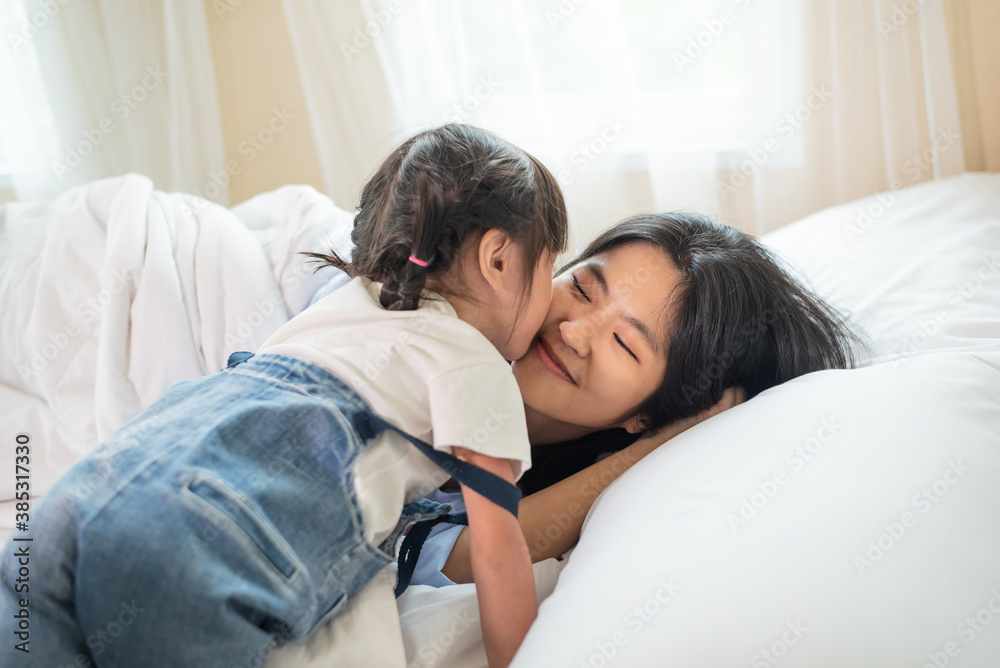 Happy Asian family loving children, kid and her sister kissing and relaxing together in bed Happy Asian family loving children, kid and her sister kissing and relaxing together in bed