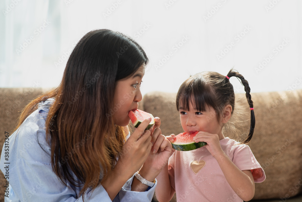 Happy Asian child enjoy eating a ripe juicy watermelon with her older sister Happy Asian child enjoy eating a ripe juicy watermelon with her older sister