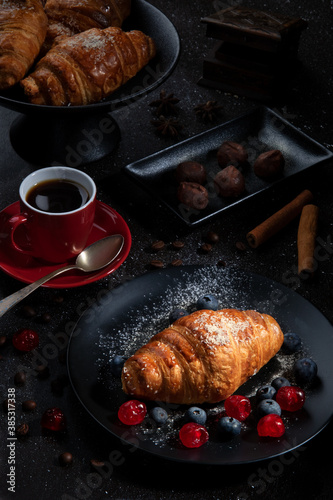 French croissants with coffee and berries, lying on a dark table. Crunchy Breakfast. Dark background..Menu and design concept.