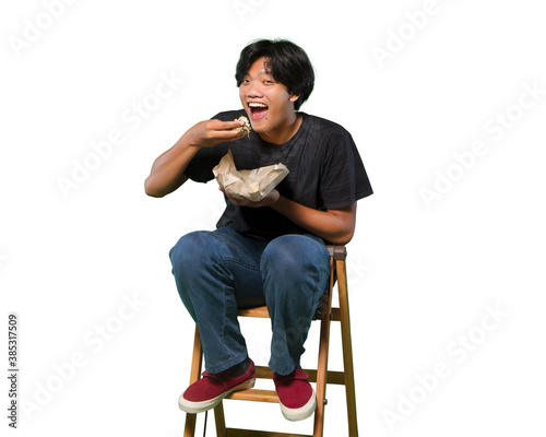 Portrait of happy young man eating nasi bungkus and looking at camera photo